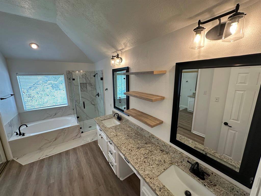 Primary bathroom with granite counters, undermount sinks, new soaking tub, and new shower with Quartz surround and frameless glass door.