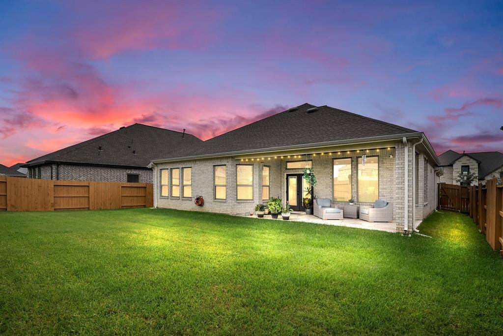 This is a single-story home featuring a brick exterior with a spacious backyard and a covered patio area, ideal for outdoor relaxation and entertainment.