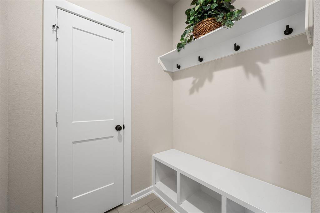 This is a tidy entryway with a built in mudroom with a built-in bench, and storage hooks.