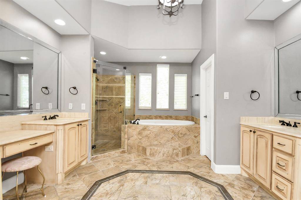 Luxurious primary bathroom with spa features including a jetted tub and large walk-in shower.