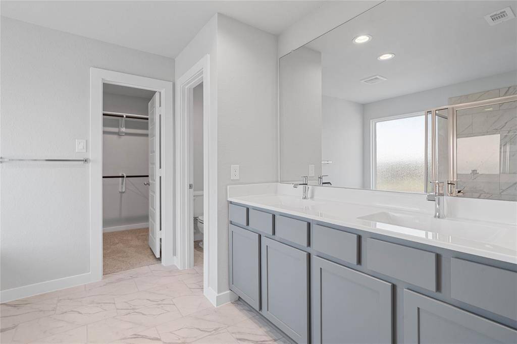 This large primary bath is spacious enough to share! With separate vanities, large closet space, plentiful cabinet and counter space, you are sure to have private area while sharing this bathroom!