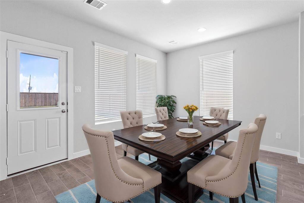 This lovely dining area is perfect for starting the day out on the right foot! This space showcases custom paint, recessed lighting, large windows with blinds, and wood look tile flooring!