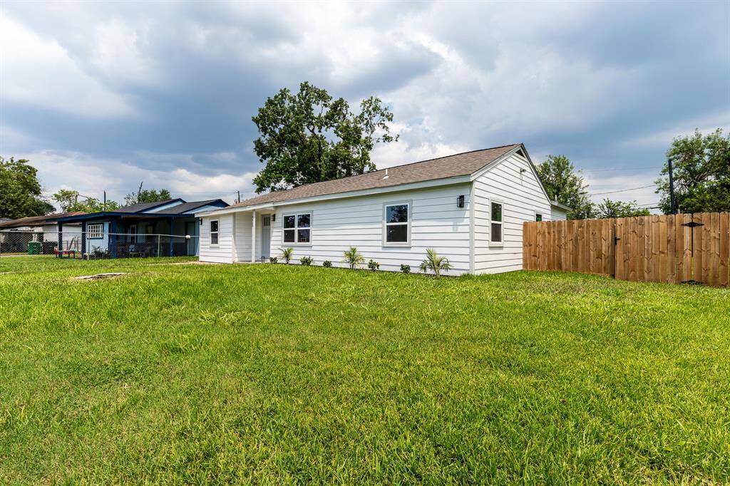 Charming single-story home with a fresh white exterior, featuring a spacious fenced backyard, in a neighborhood with mature trees.