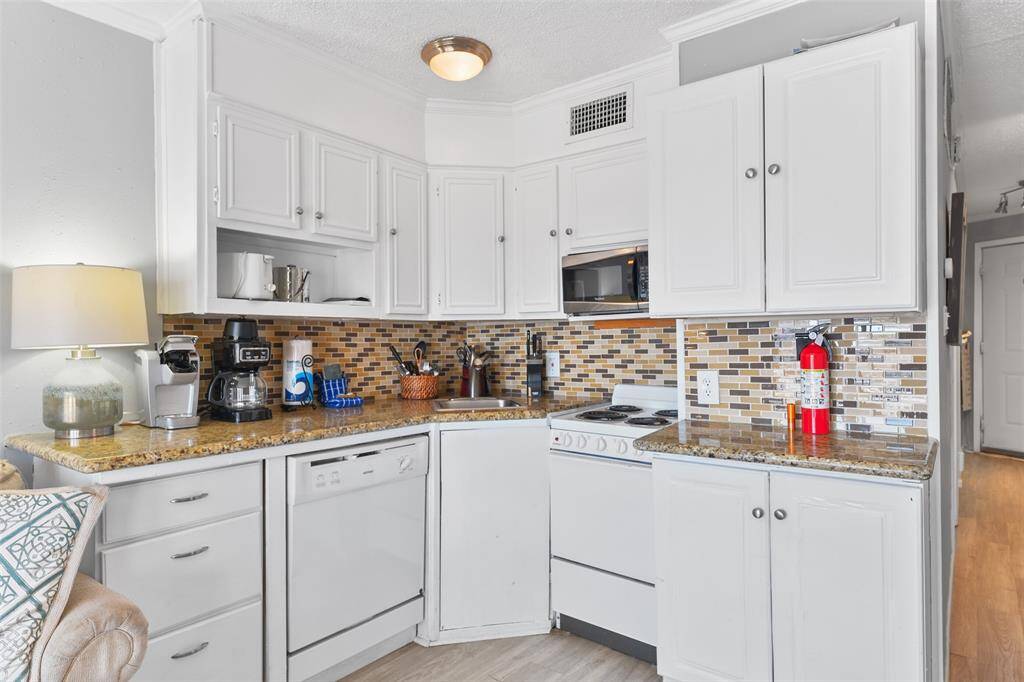 This compact kitchen is thoughtfully designed with plenty of cabinet storage, an electric stove, microwave, and dishwasher, making meal prep a breeze.