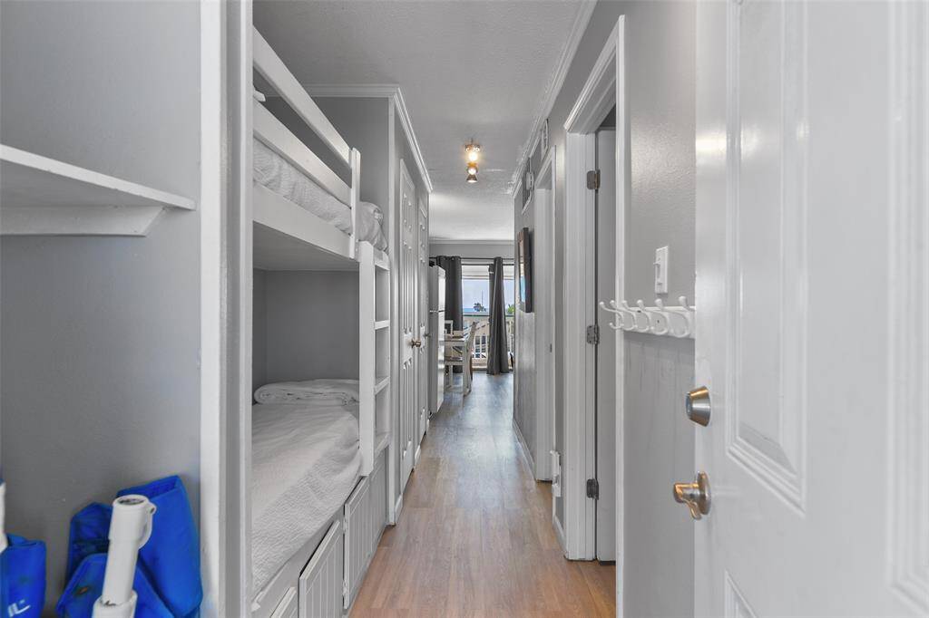 This charming hallway features built-in bunk beds, perfect for added sleeping space, entrance storage and a owner's closet while leading to both the bedroom and bathroom for easy access.