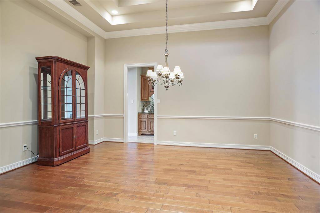Experience elegance with the dining room's rich wooden flooring and classic chair rail detailing, seamlessly flowing into an inviting dry bar area.