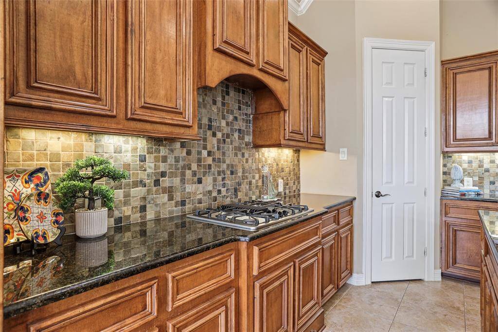 Enjoy culinary creations on the sleek gas cooktop, complete with an efficient downdraft system and surrounded by elegant, custom tile work.