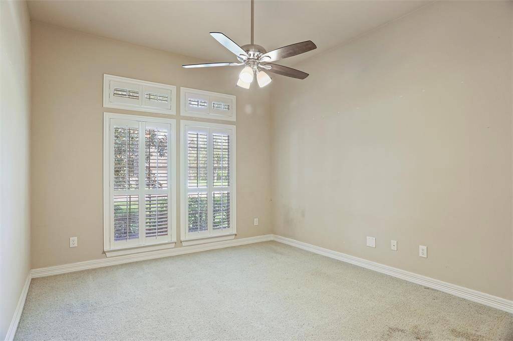 Enjoy serene views of the front yard from the comfort of the third bedroom, graced with elegant plantation shutters.