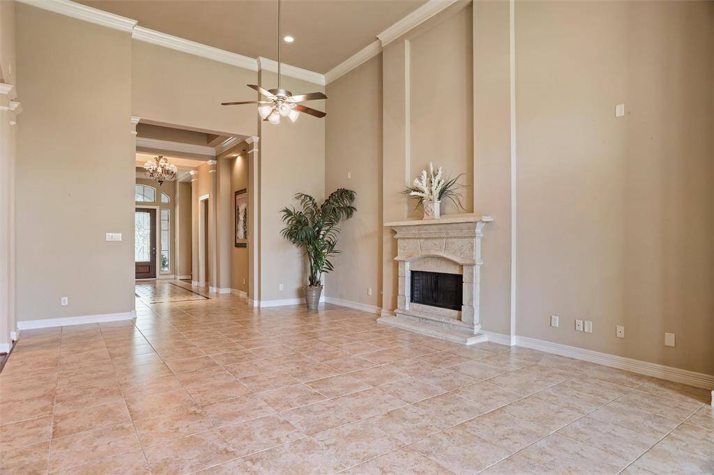 Experience the grandeur of this elegant living room, boasting soaring 16-foot ceilings and seamless flow into the adjacent dining and family rooms, with convenient access to a versatile outdoor kitchen.