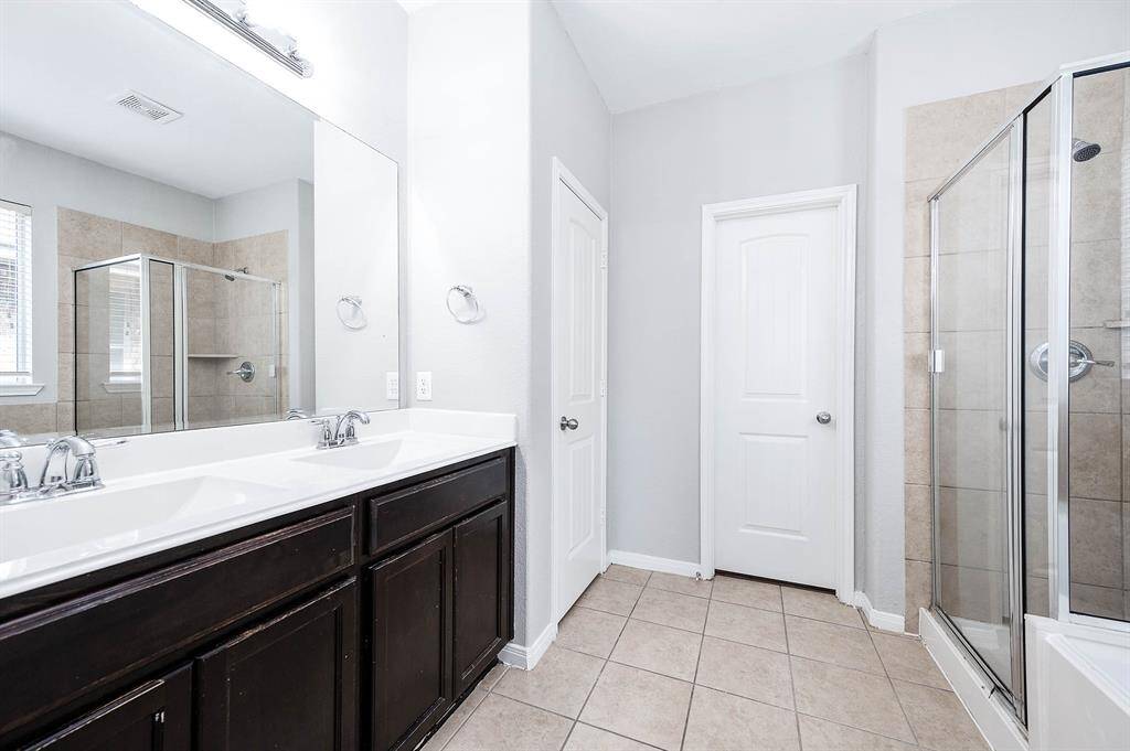Ensuite primary bathroom featuring dual sinks and separate soaking tub and walkin shower.
