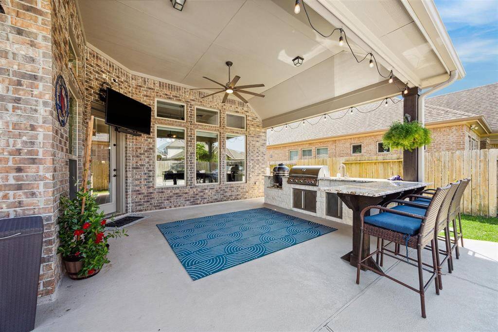 Stunning outdoor kitchen with green egg, BLAZE grill, sink and storage.   Large granite peninsula with ample seating.  Rope lights; oversized ceiling fan.