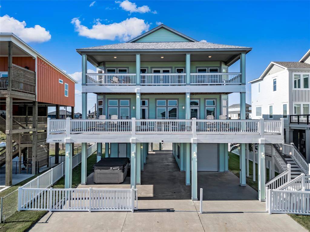 This is a modern three-story 2nd row coastal home with dual balconies, a light blue exterior, and covered fenced parking.