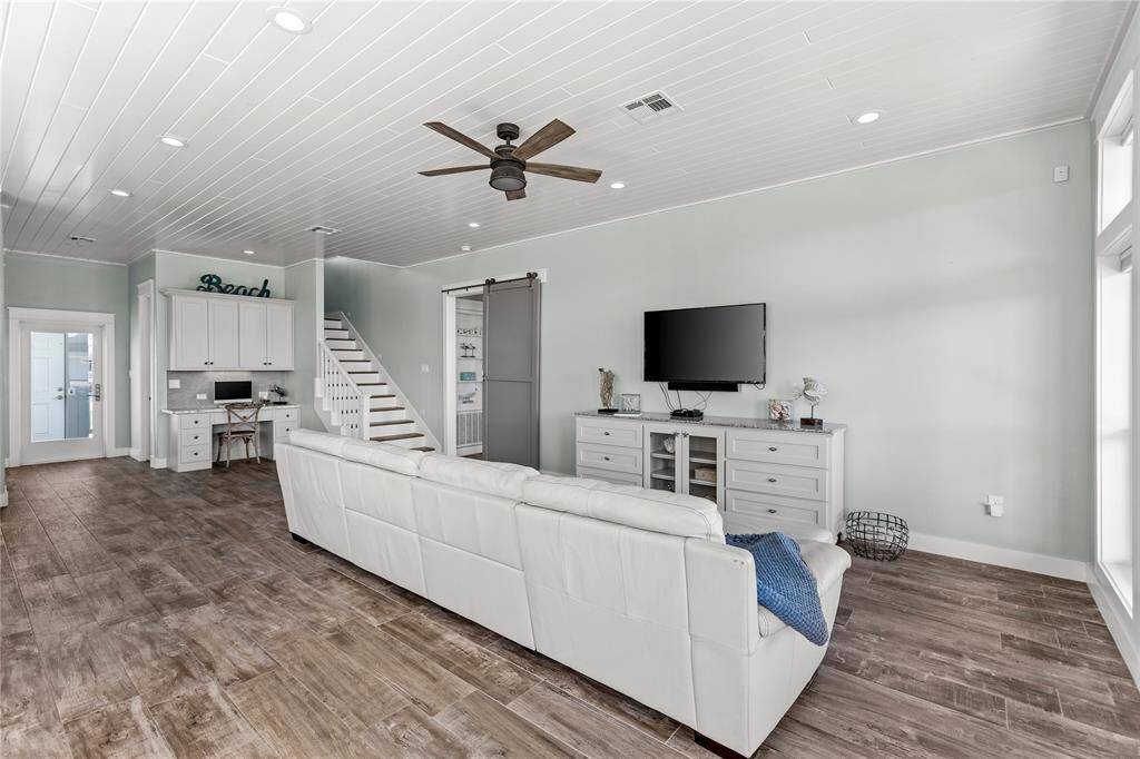 Bright, open-concept living space featuring a clean, coastal design with a soft color palette, wood-look luxury vinyl flooring, and shiplap ceiling.