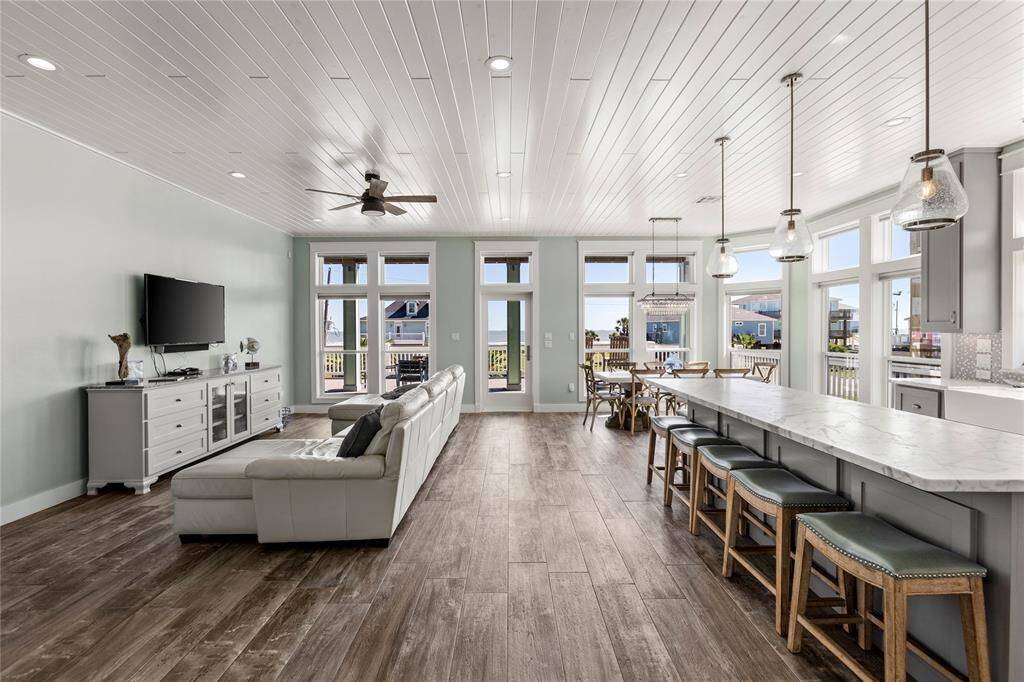 This is a bright, open-plan living space featuring a modern kitchen with a large honed statuary marble countertops island and bar seating.