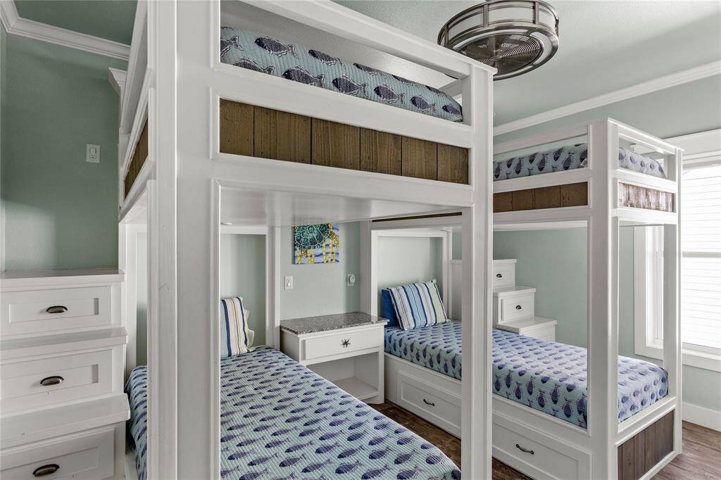 2nd floor well-appointed bedroom with two sets of white, built-in bunk beds with storage drawers, accented by a fresh, seafoam green wall color.