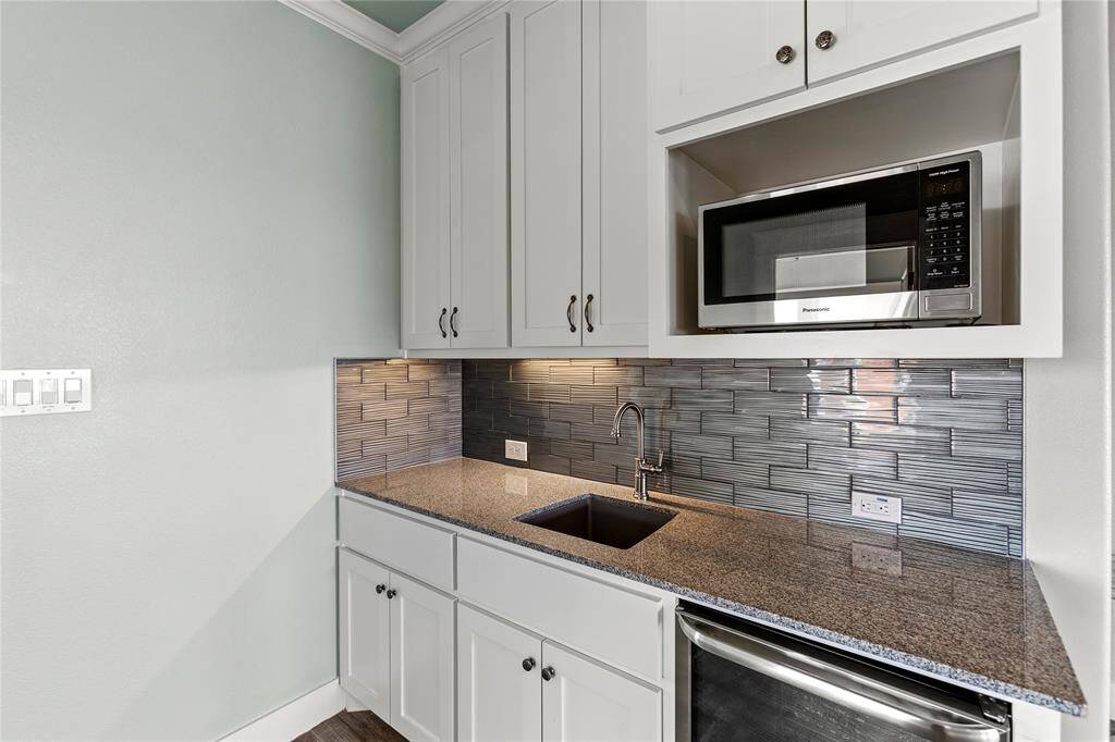 2nd floor kitchenette with sleek cabinetry, granite countertops, stainless steel microwave and wine fridge.