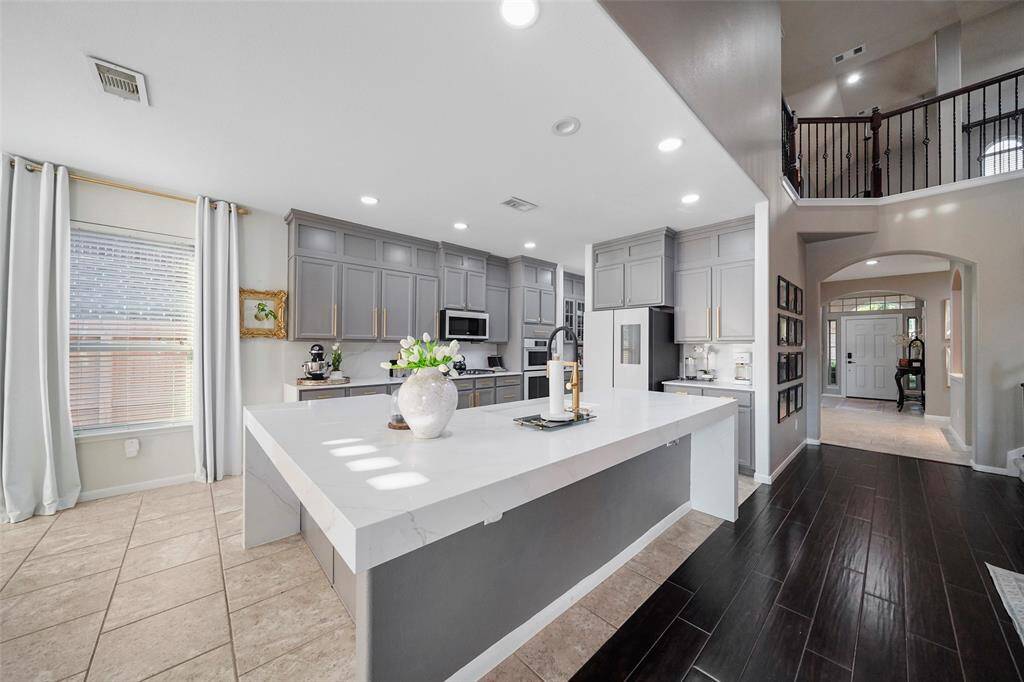 View of the waterfall island with overhang for additional seating. Entry foyer and second floor game room beyond.