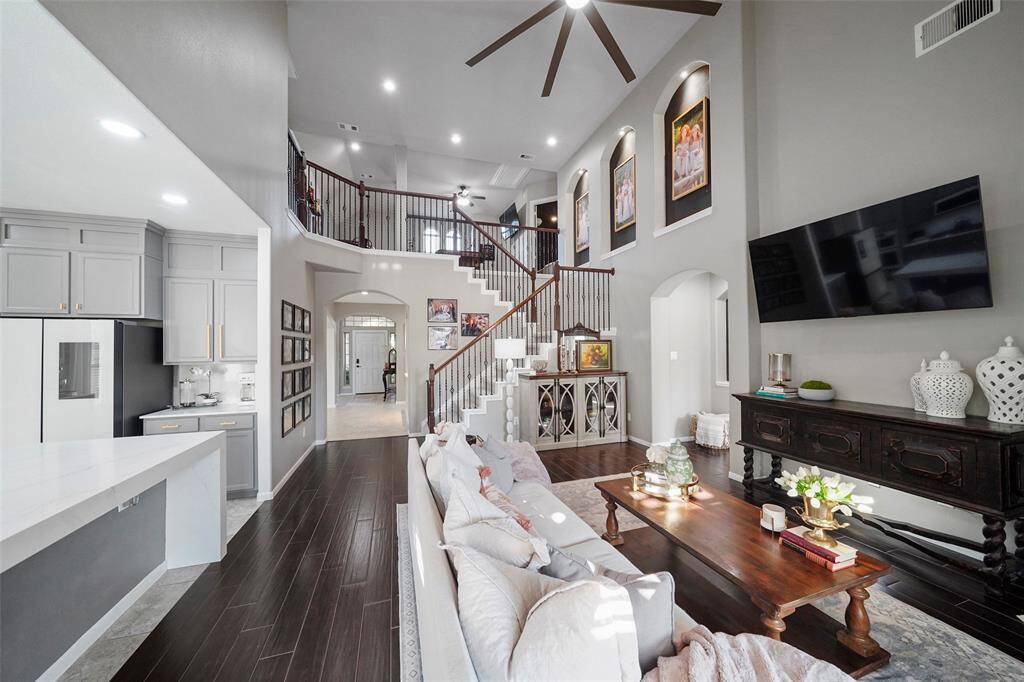 The two story living room is grand and updated with modern style ceiling fan, wood flooring and neutral paint. At the top of the stairs, is the game room, media room and three guest bedrooms.