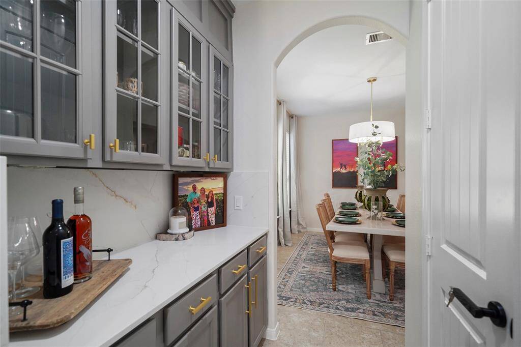 A butlers pantry connects the formal dining room to the kitchen. Quartz countertops, updated cabinet hardware and glass front cabinets updates this space for a more modern look. A large walk in pantry is to the right.