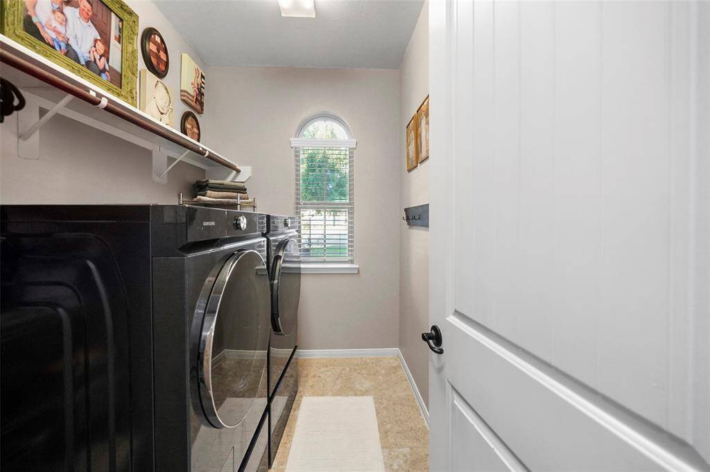 Large laundry room off of the entry and garage area with arched window overlooking the front porch. Shelves provide storage and hanging space.