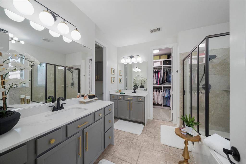 The updated primary bath features quartz countertops with modern waterfall edge, updated lighting and coordinating hardware. Separate toilet room and closet are beyond.