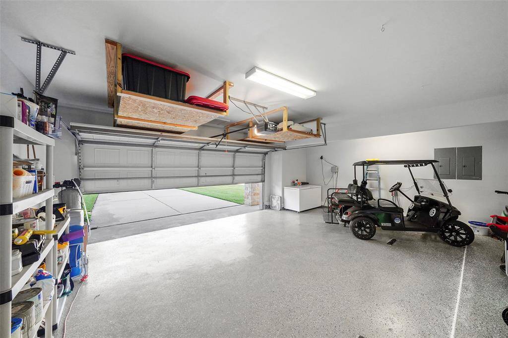 Garage space with extra overhead storage, epoxy floor finish and extra area storage beyond.