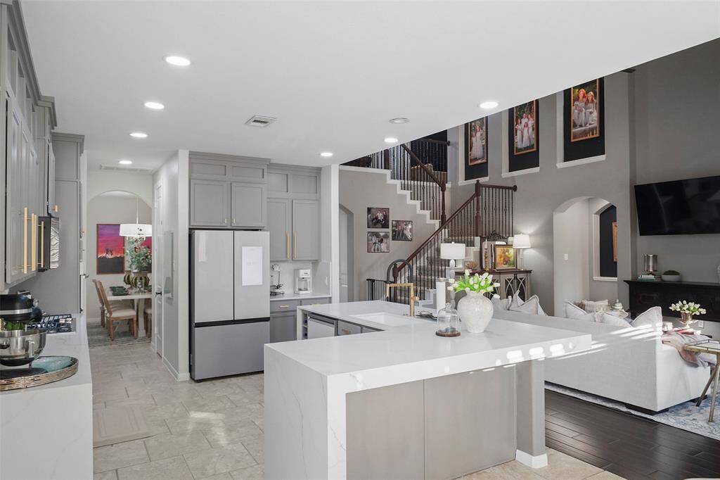 The updated kitchen features Samsung Bespoke series appliances, quartz countertops, modern brushed gold hardware and updated cabinets. Kitchen is open to the living room for an open concept plan.