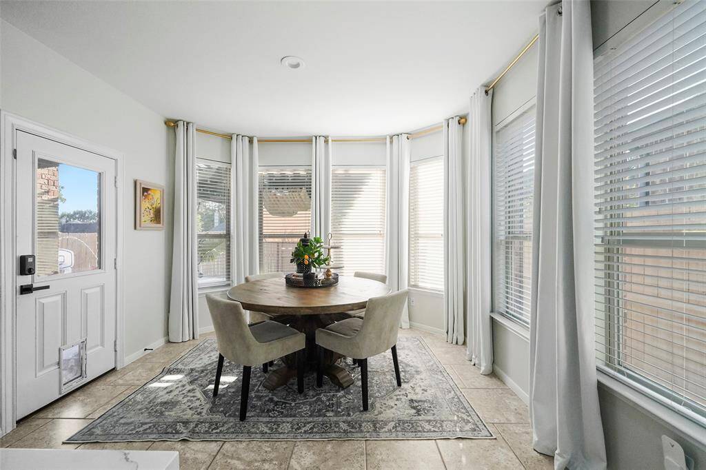 A bright and airy breakfast room is surrounded by windows overlooking the back and side yards. Glass door leads to the back porch.