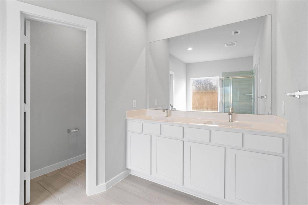 This primary bathroom is definitely move-in ready! Featuring dual vanities, stained wood cabinets with light countertops, spacious walk-in closet with shelving, high ceilings, custom paint, sleek and modern finishes.