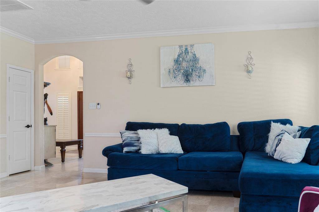 The family room/den, overlooking the backyard, is filled with natural light and features plantation shutters. It opens up to the kitchen, creating a spacious open-concept design.