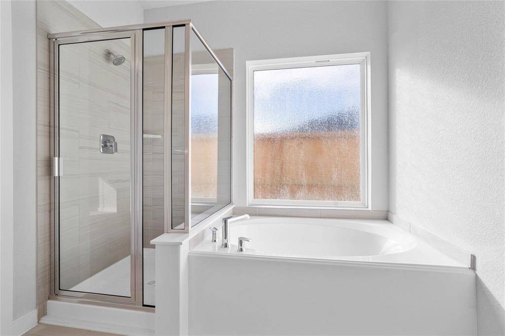 Additional view of the primary bathroom featuring a walk-in shower with tile surround and a separate garden tub for soaking after a long day.