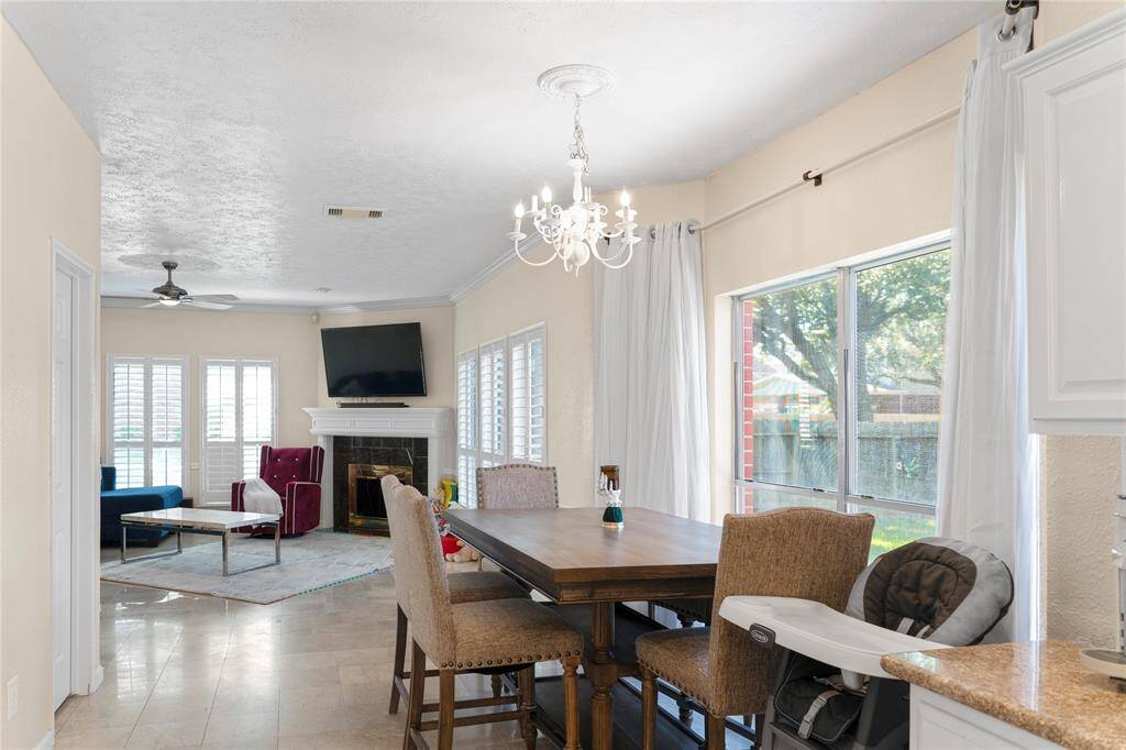 The family room/den, overlooking the backyard, is filled with natural light and features plantation shutters. It opens up to the kitchen, creating a spacious open-concept design.