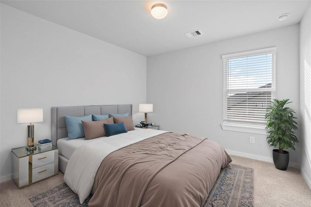 Secondary bedroom features plush carpet, neutral paint and a large window with privacy blinds.