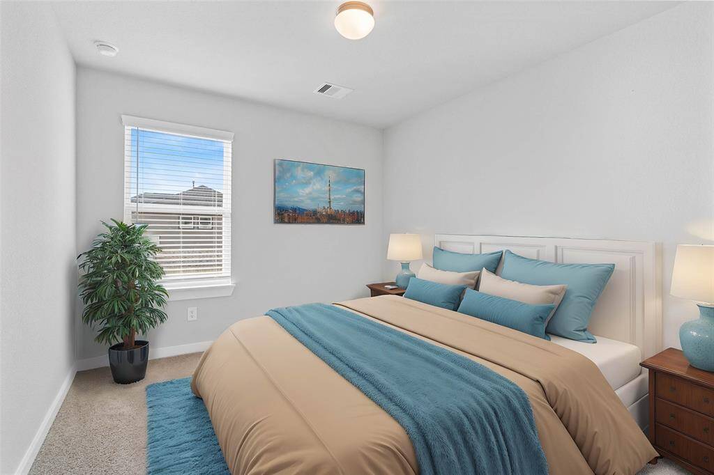 Secondary bedroom features plush carpet, neutral paint and a large window with privacy blinds.