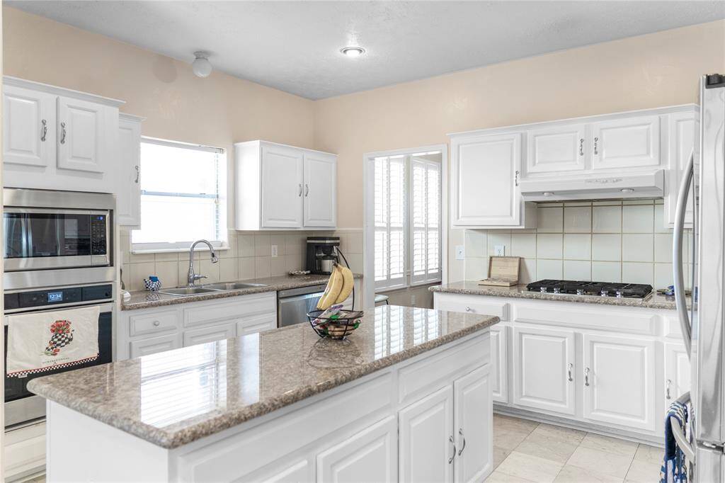 A spacious kitchen equipped with granite countertops and stainless steel appliances, ideal for cooking.