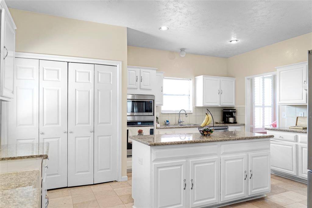 A spacious kitchen equipped with granite countertops and stainless steel appliances, ideal for cooking.