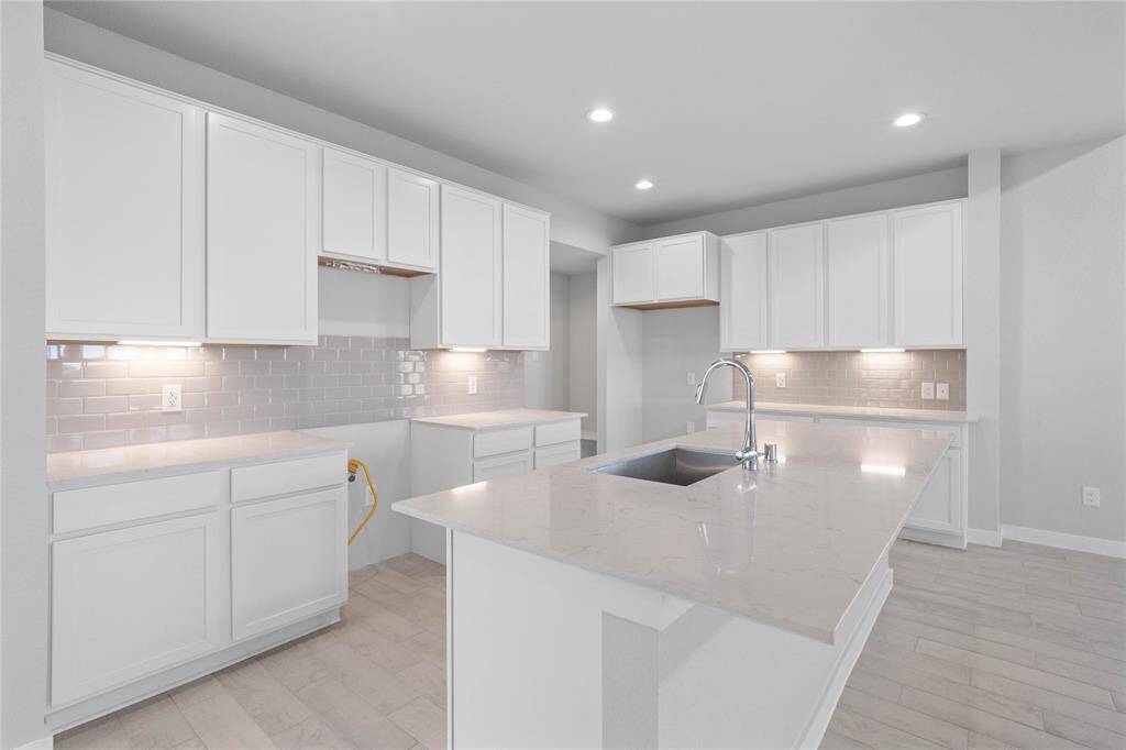 This stunning kitchen displays such beautiful stained cabinets, custom neutral paint, granite countertops, modern backsplash, oversized kitchen island with extra storage, breakfast bar, recessed lighting, high ceilings and walk in pantry.