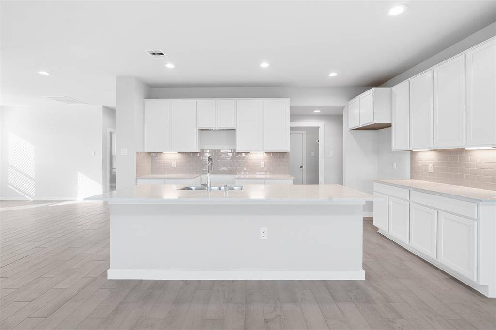 This stunning kitchen displays such beautiful stained cabinets, custom neutral paint, granite countertops, modern backsplash, oversized kitchen island with extra storage, breakfast bar, recessed lighting, high ceilings and walk in pantry.