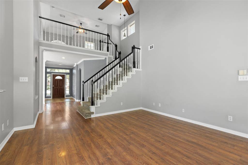 Sizable living area with ceiling fan and two story ceiling height.
