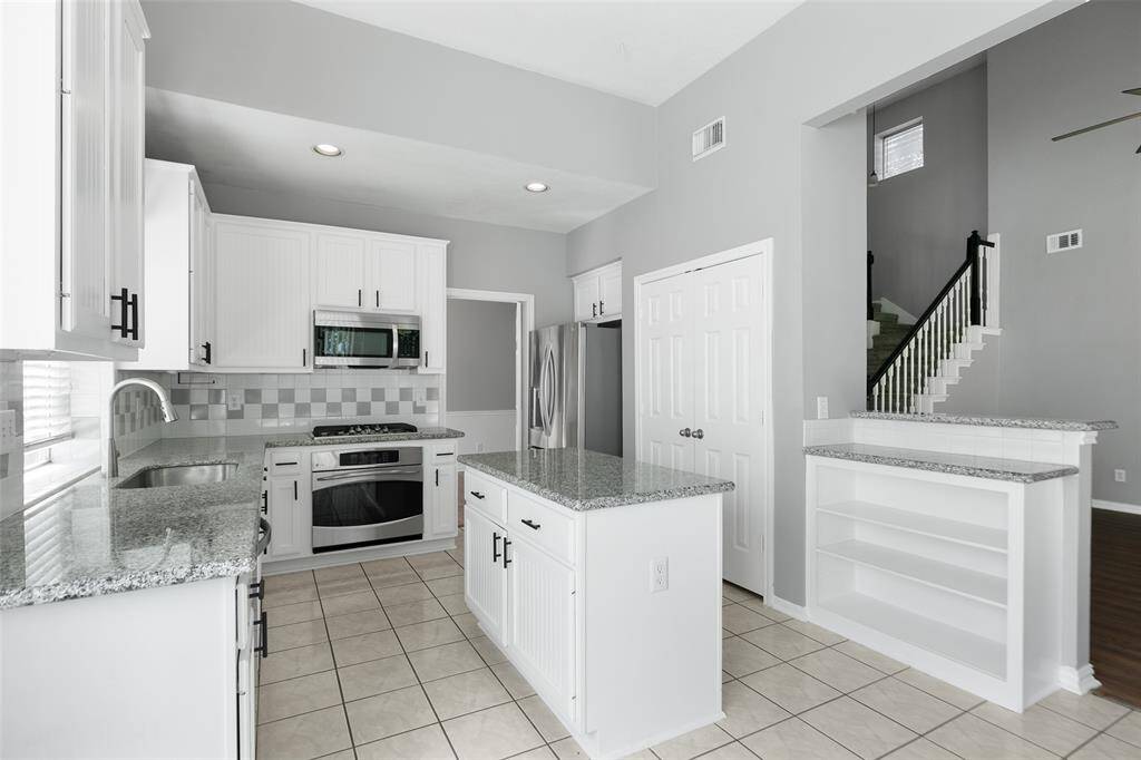 Granite counters and kitchen island with elegant grey ceramic accented backsplash.
