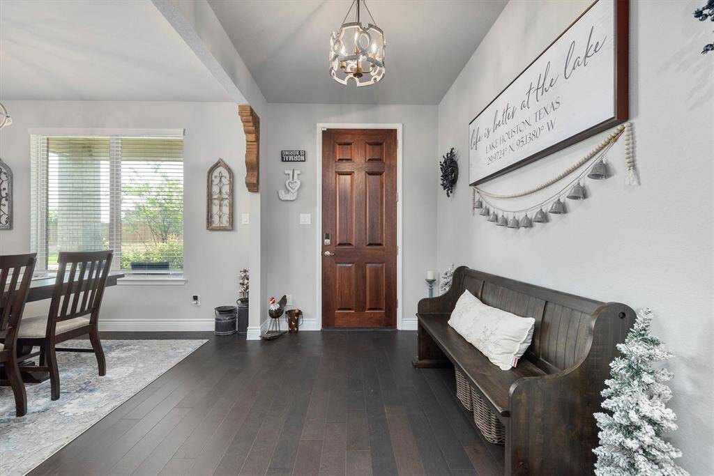 The photo showcases beautiful dark wooden floors with a spacious entryway boasting tall ceilings, a wooden staircase, and an inviting, well-lit interior.