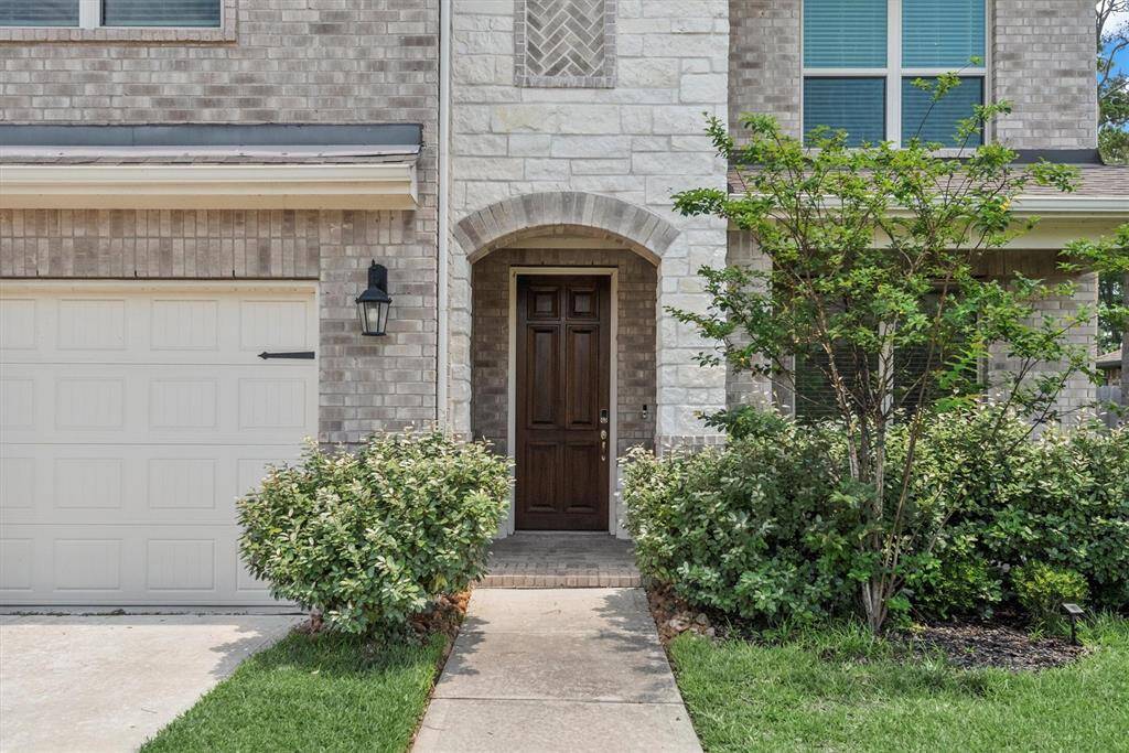 Enjoy this beautiful stone entrance as you walk through the front door, with its elegant arched design and sturdy wooden door complemented by lush greenery.