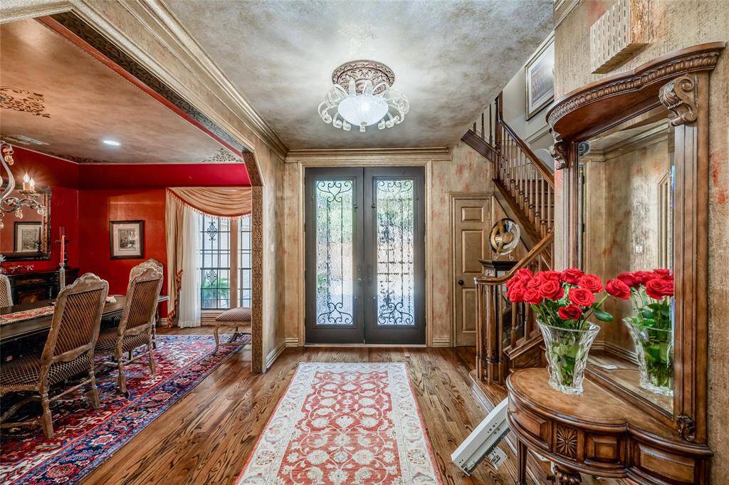 Step through the striking wrought iron French doors with glass panels into a spacious foyer with 9-foot ceilings, gleaming hardwood floors, and double crown moulding. Note the gold faux painted paneled door leads to a walk-in storage closet with custom shelving.
