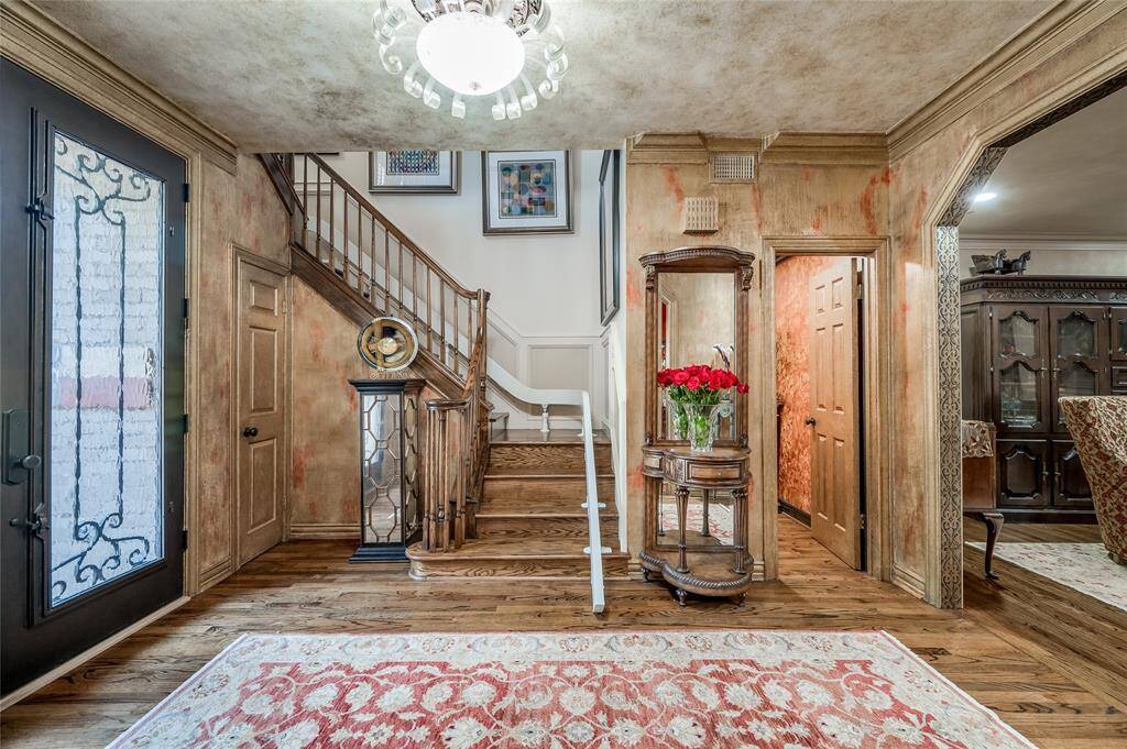 From this vantage point, admire the spacious foyer, featuring a half bathroom, the stairway with chair rail molding, and the intricate stencil work along the archways.