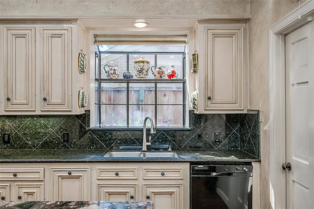 A closer view highlights the granite countertops and coordinating backsplash, enhanced by undercabinet lighting and a large garden window.