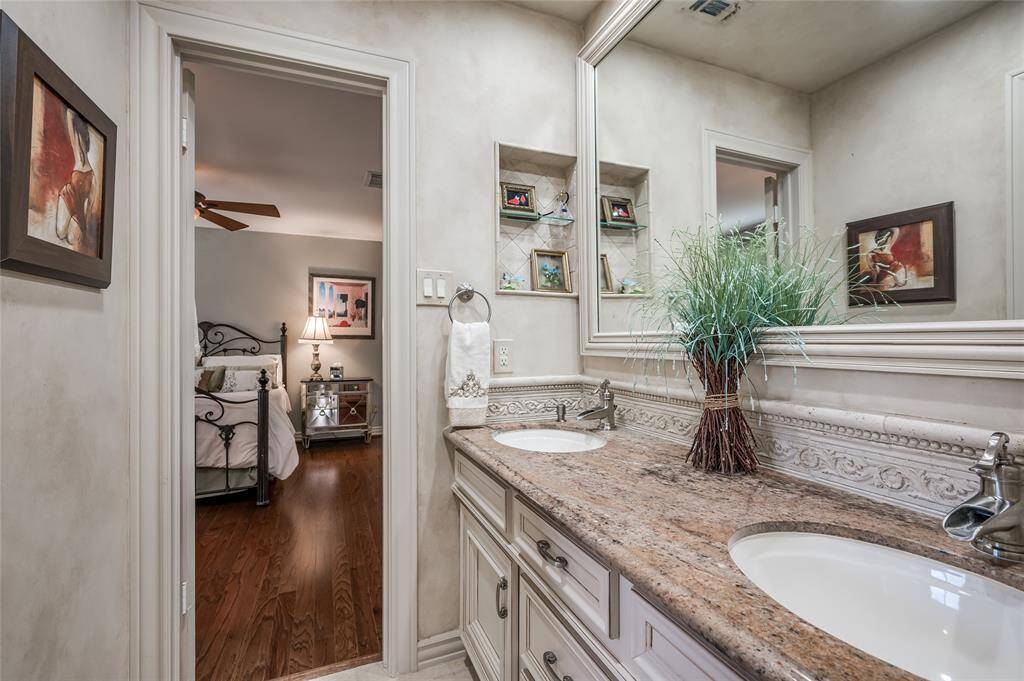 This Hollywood bathroom provides seamless functionality, connecting two bedrooms while offering a separate shower/tub combination and toilet room space. The bathroom features granite countertops, dual undermount sinks, tile flooring and a custom vanity mirror.