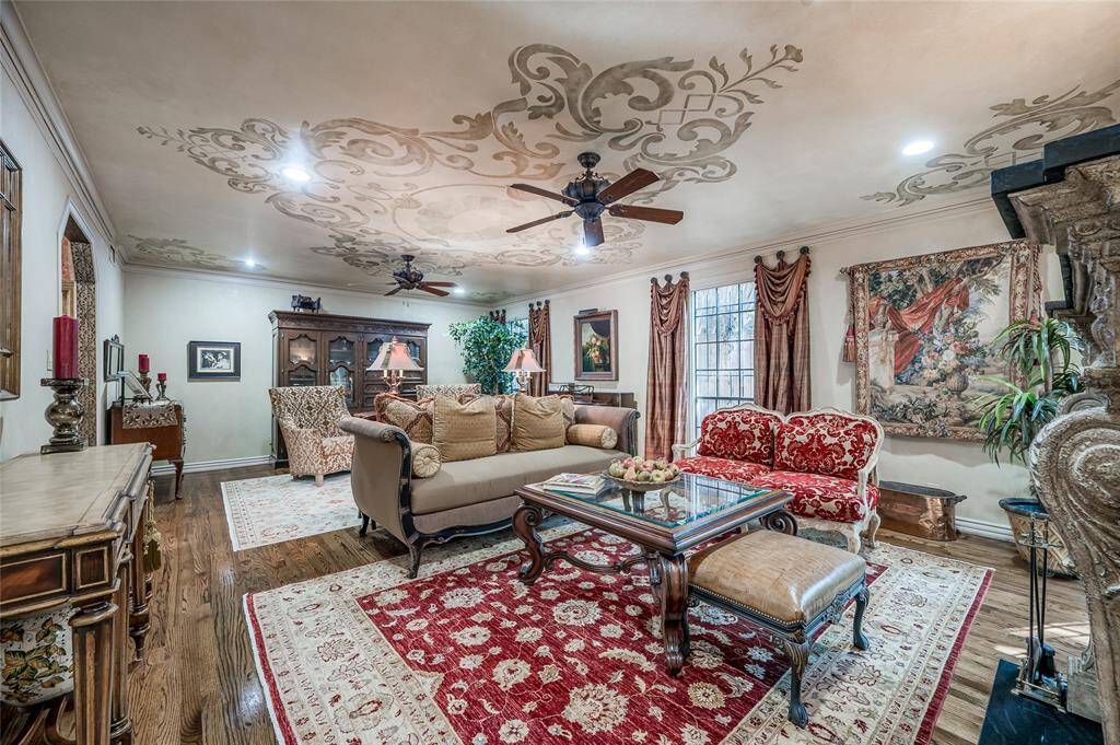 Spacious and welcoming, the formal living room features custom stenciling on the ceilings, hardwood floors, and subtle recessed lighting.