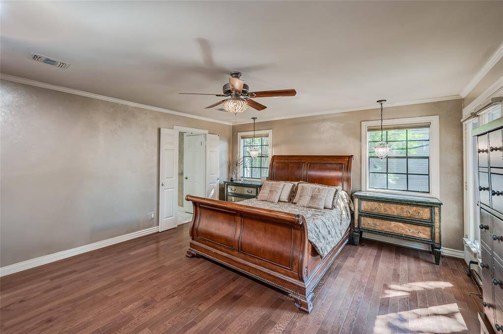 The primary bedroom features hardwood floors, 8-foot ceilings, and direct access to the luxurious en-suite primary bathroom and second floor balcony.