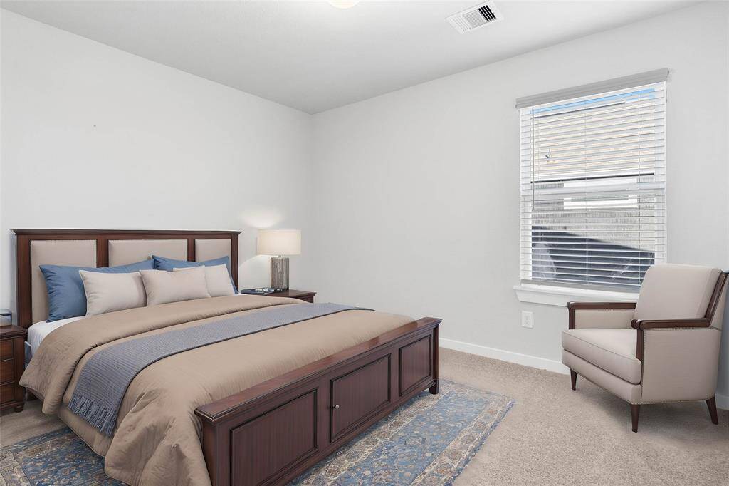 Secondary bedroom features plush carpet, custom paint, high ceilings, and a large window with privacy blinds.