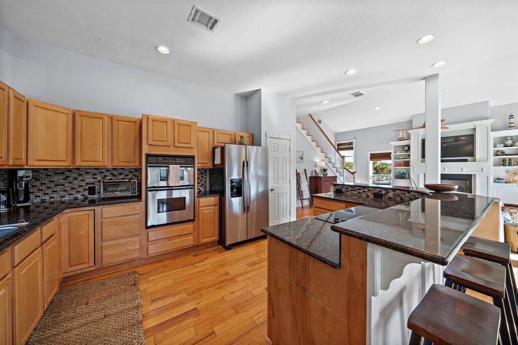 Stainless steel appliances complement the spacious cabinetry. The warm wood floors add a cozy contrast to the modern finishes, creating a perfect space for cooking and entertaining.